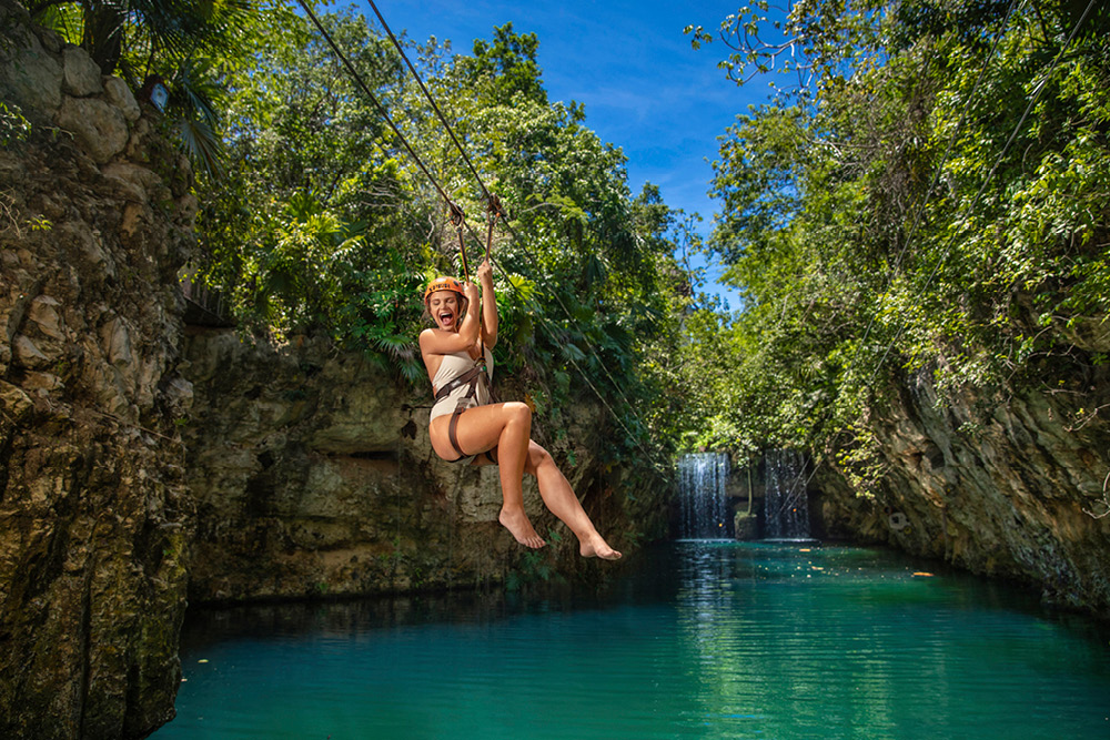 Woman ziplining in one of Grupo Xcaret's natural water parks