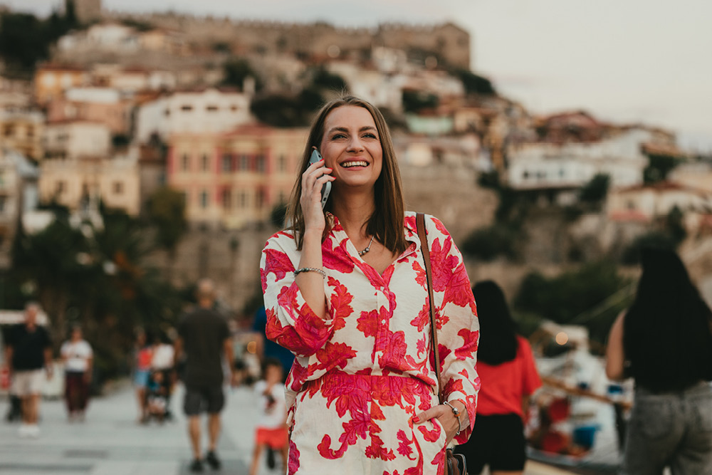 Woman walking in a foreign city and speaking on the phone with a travel insurance representative