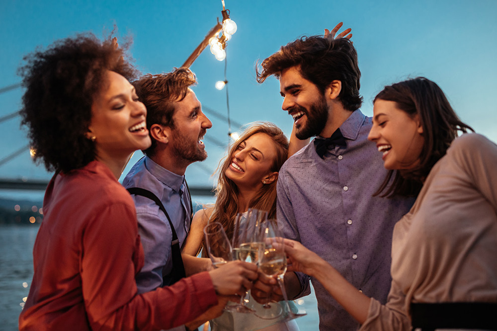 Group of four wedding guests in semi-formal attire clinking glasses of champagne