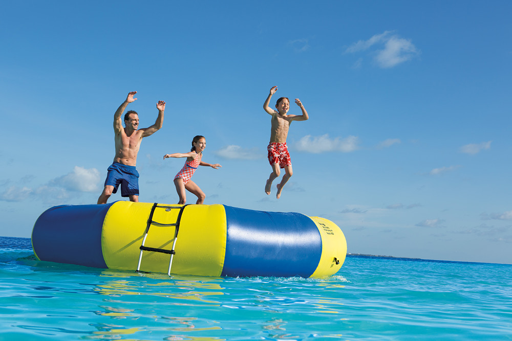 Family jumping on water trampoline at Dreams® Sands Cancun Resort & Spa