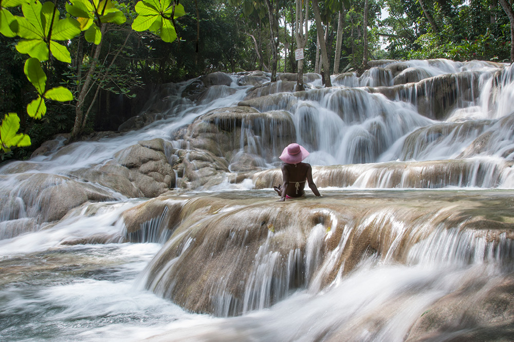 Woman sitting in natural pool formed by Dunn's River Falls in Jamaica