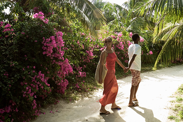 Couple walking along path lined with tropical plants and flowers