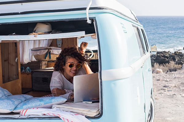 Woman relaxing in converted van beside a beach