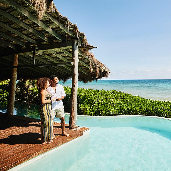 A couple looks over a pool on vacation