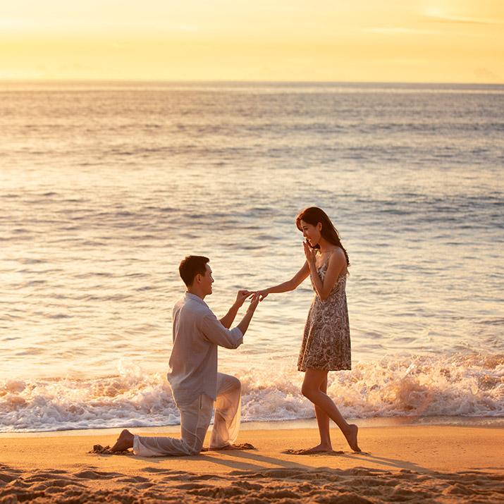 Couple getting engaged on the beach at sunset