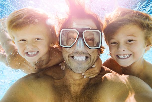 A father and his sons snorkel while on a family vacation