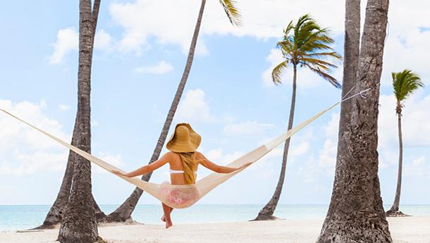 A woman sits on a hammock on vacation