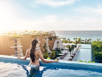 Woman standing in pool overlooking a Hoteles Xcaret resort