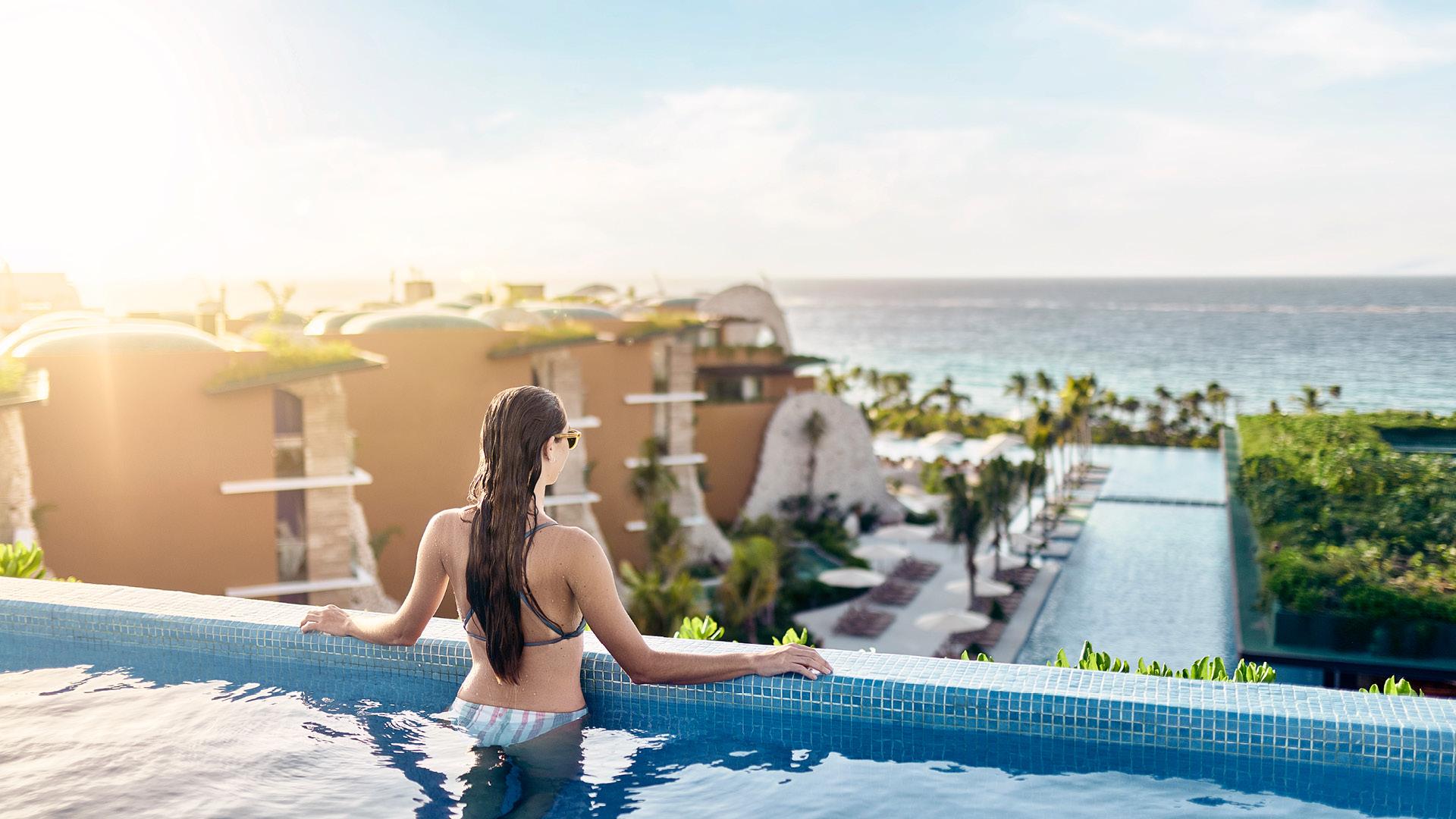 Woman standing in pool overlooking a Hoteles Xcaret resort