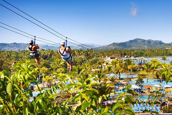 Couple ziplining over tropical resort