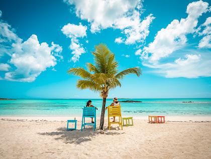 Women sitting in colorful lifeguard chairs on a tropical beach