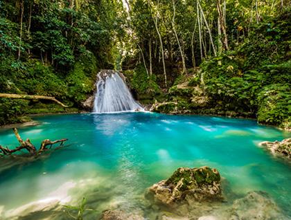 Waterfall flowing into a clear blue swimming hole in Jamaica