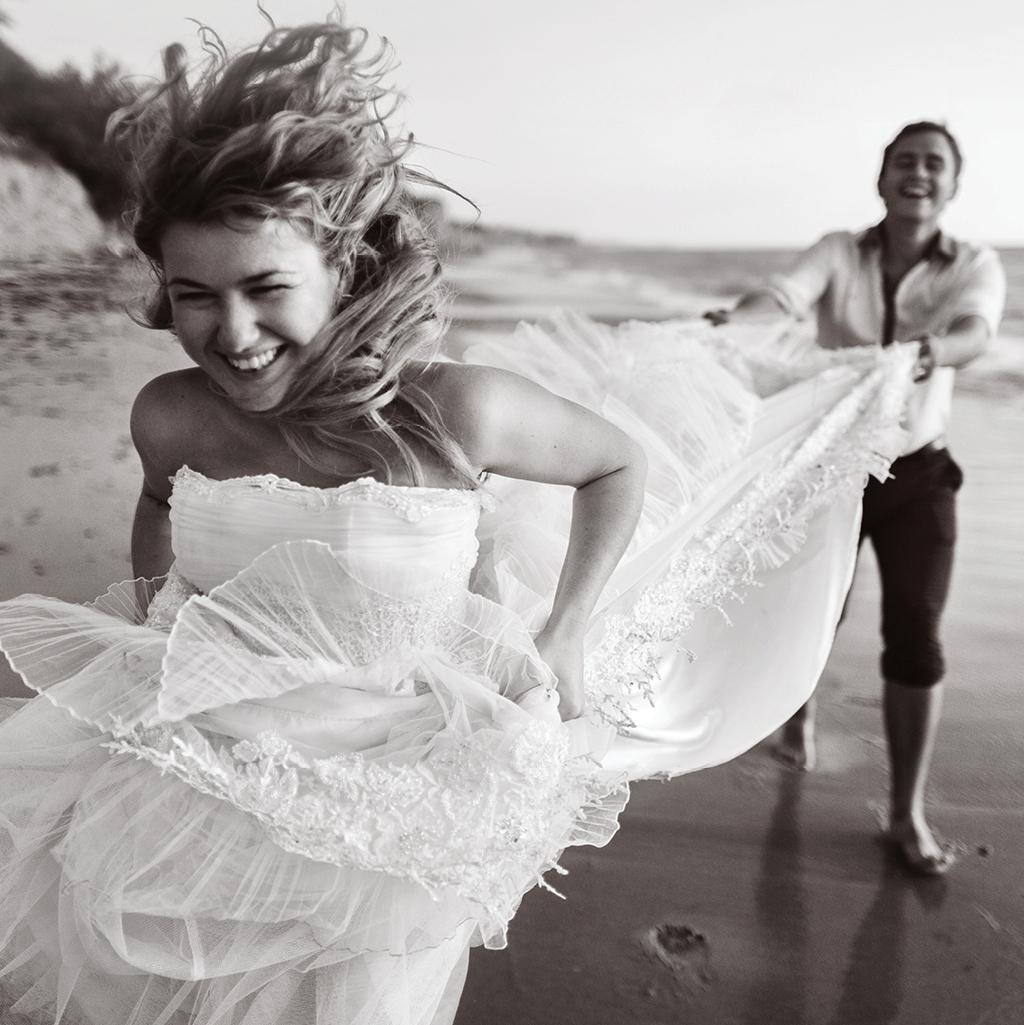bride and groom frolicking on a beach