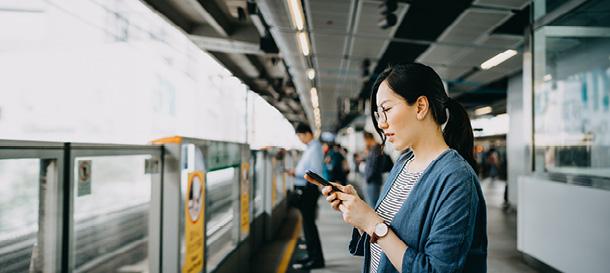 A woman looks at her phone while at a train station