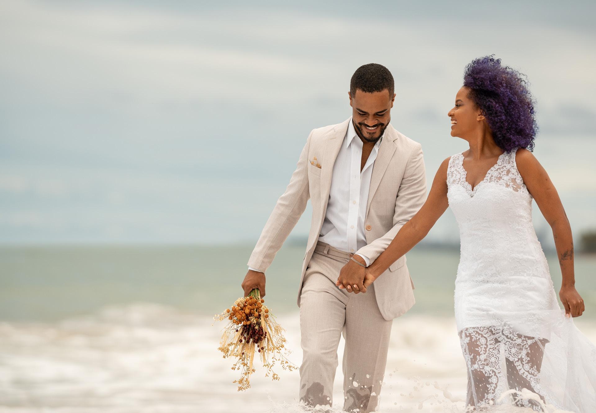 A couple walks along the beach after their destination wedding