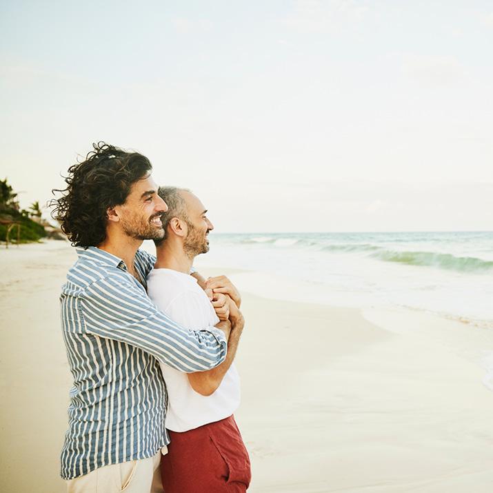 A gay couple embrace on their beach vacation