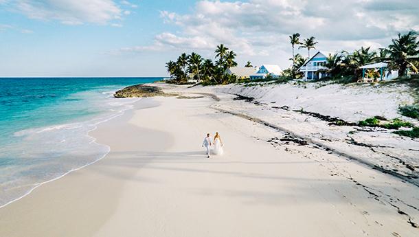 A newlywed couple walk along a beach