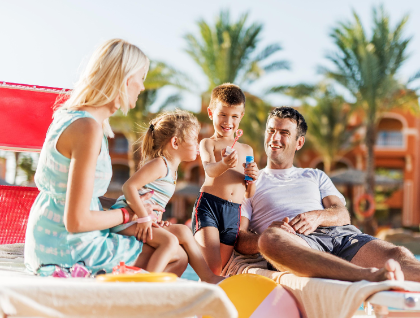 Family of four sitting and playing on loungers at a Caribbean resort