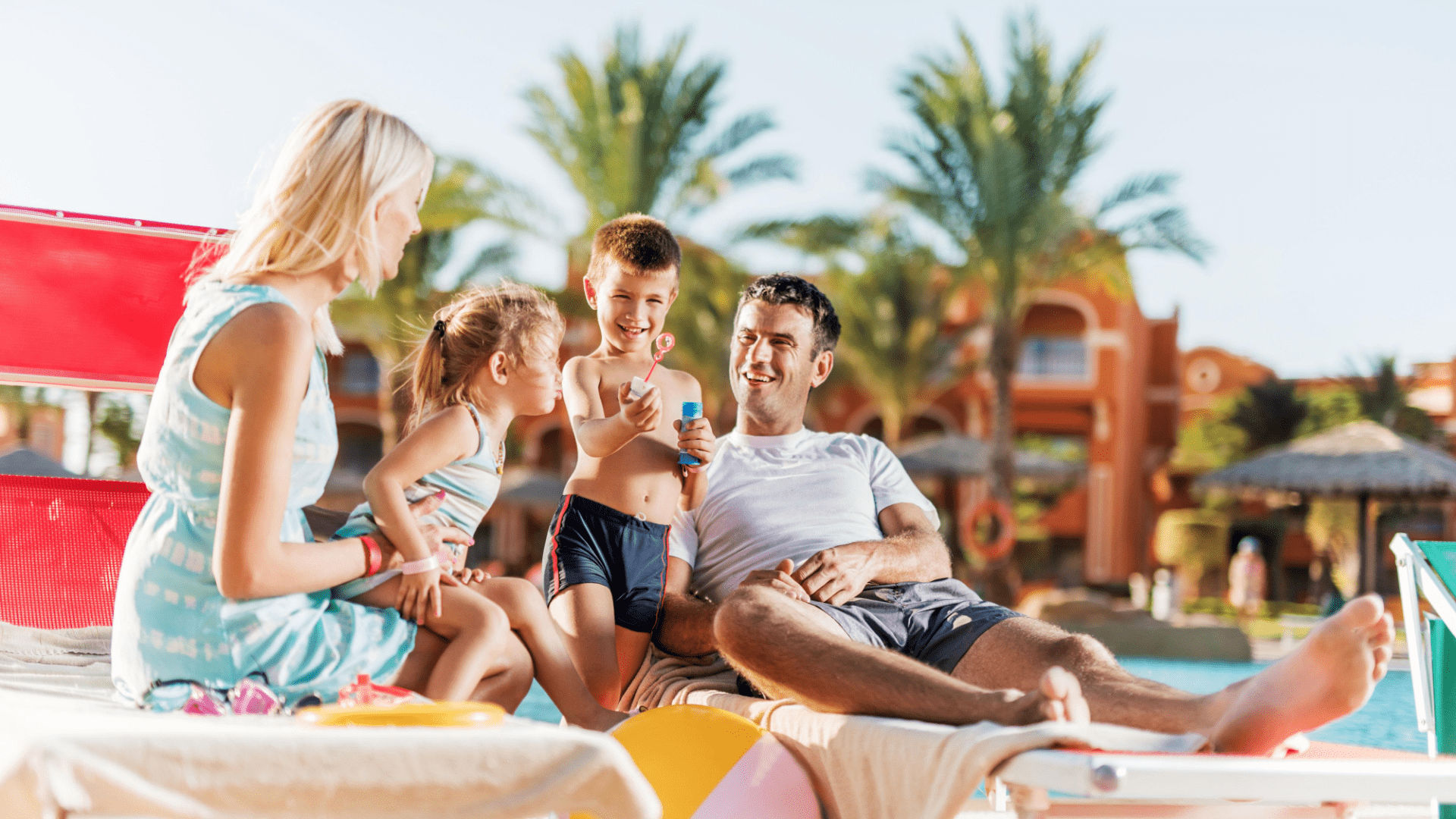 Family of four sitting and playing on loungers at a Caribbean resort