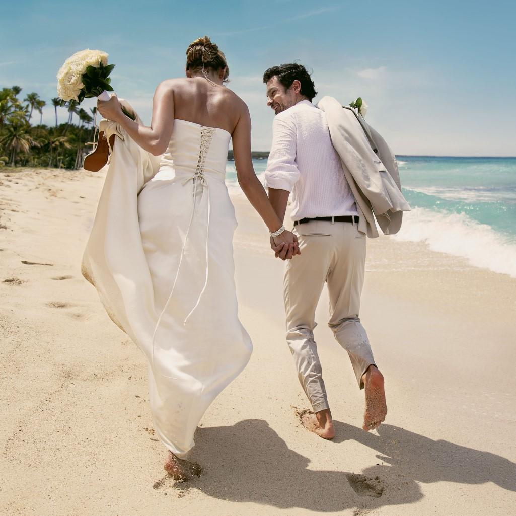 A newlywed couple walks along the beach